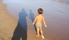 Chlapeček jdoucí po pláži u moře 