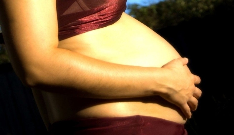Žena držící si těhotenské bříško