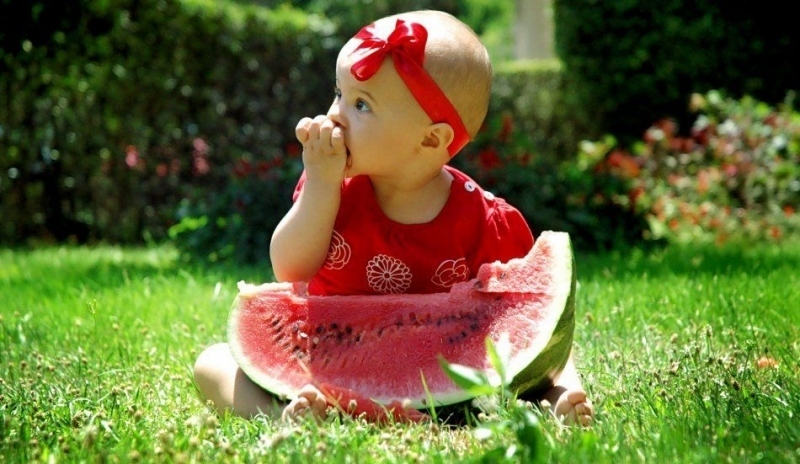 Dítě s melounem sedící na trávě 