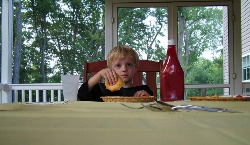 Chlapec sedící za stolem u jídla 
