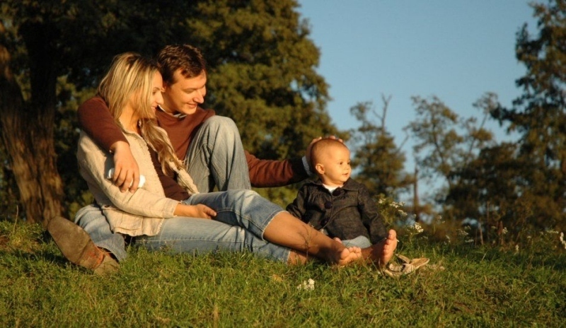 Dospělí s dítětem sedící na trávě 