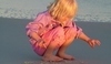 Holčička hrající si na písečné pláži 