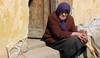 Stará žena sedící u dveří 