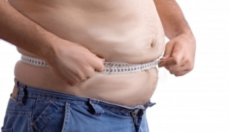 Obézní muž s omotaným metrem kolem břicha 