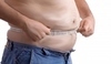 Obézní muž s omotaným metrem kolem břicha 