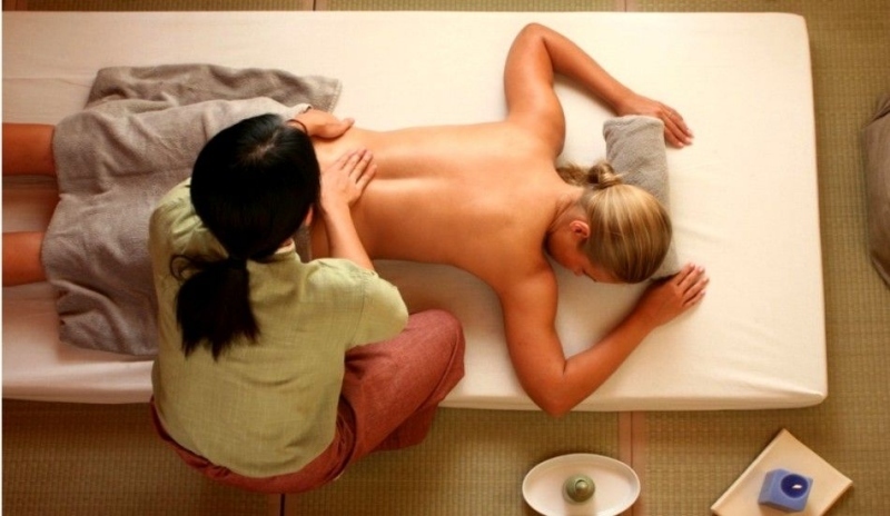 Žena provádí masáž ležící osobě 