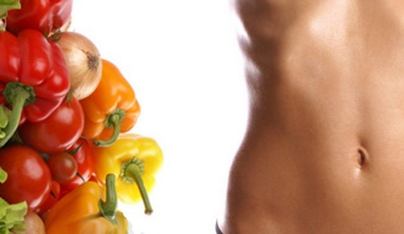 Ženské břicho vedle papriky,rajčat a cibule 