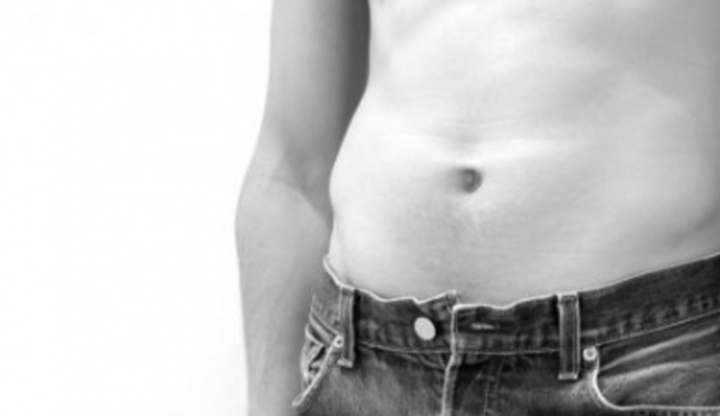 Detail odhaleného mužského břicha v kalhotech