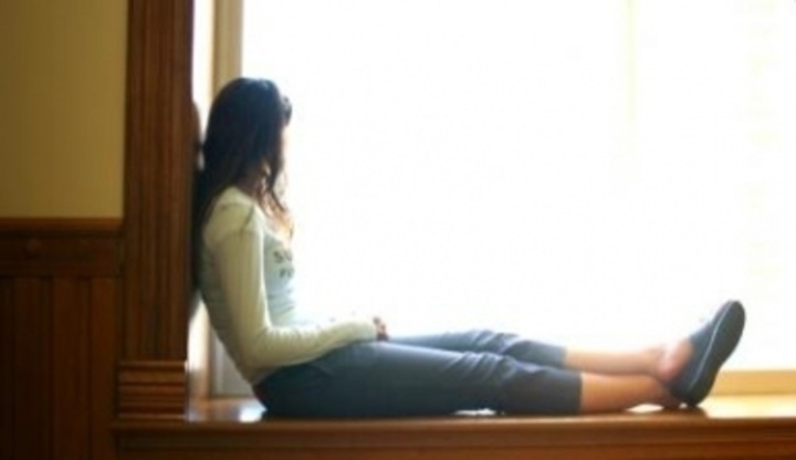 Žena sedící na parapetu okna