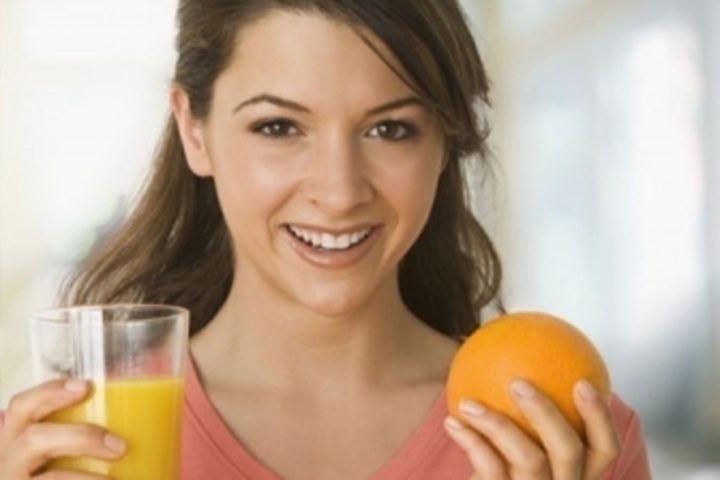 Žena držící sklenici džusu a pomeranč