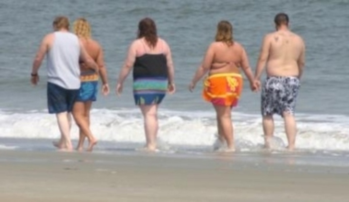 Obézní lidé procházející se na pláži