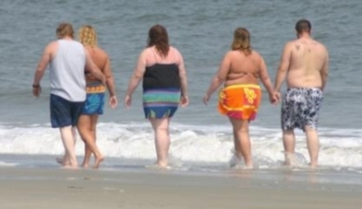 Obézní lidé chodící po pláži