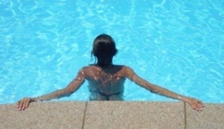 Žena v bazénu držící se jeho okraje 
