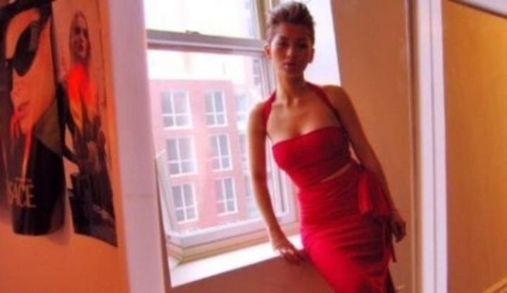 Žena v červených šatech stojící u okna