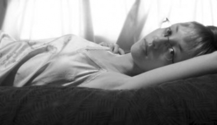 Černobílá fotografie ležící ženy s brýlemi 
