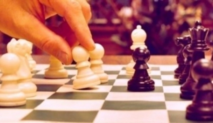 Ruka posouvající bílou šachovou figurku po hracím poli