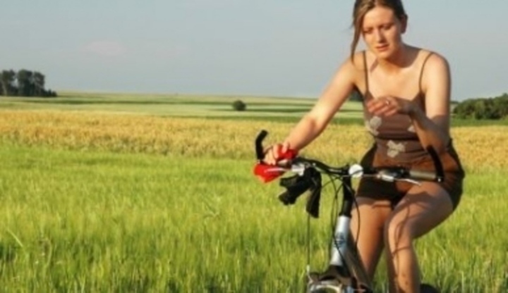 Žena jedoucí na kole kolem louky