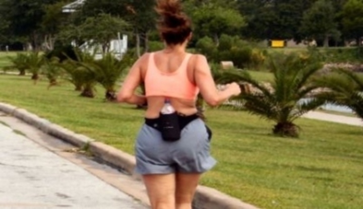 Obézní žena běžící s připnutou láhví na zádech