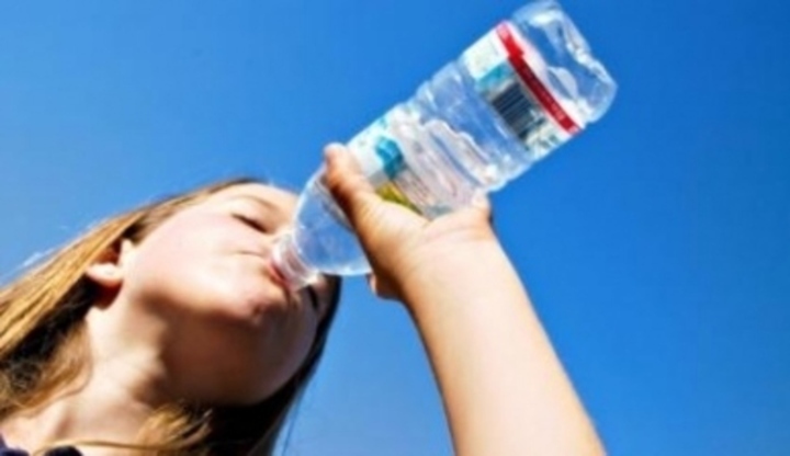 Žena pijící vodu z plastové láhve 