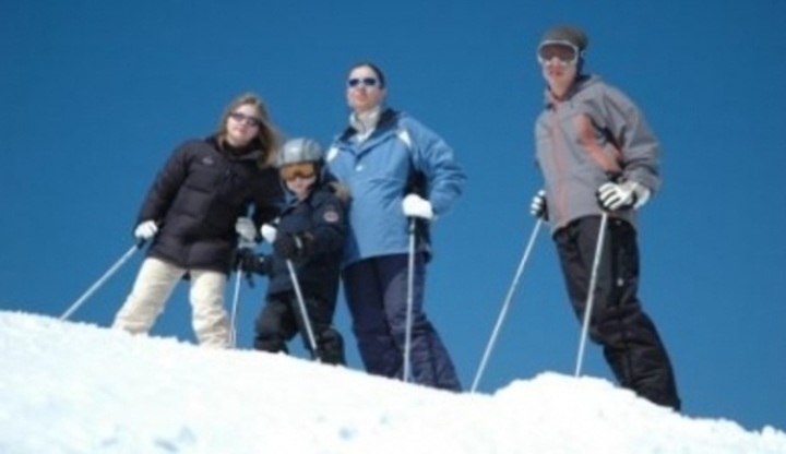 Lidé v lyžařském oblečení stojící na zasněženém kopci