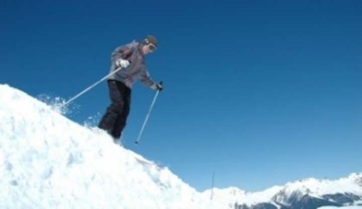 Muž sjíždící na lyžích zasněžený kopec
