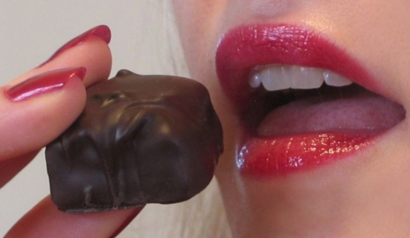 Čokoládový bonbon směřující k ústům ženy 