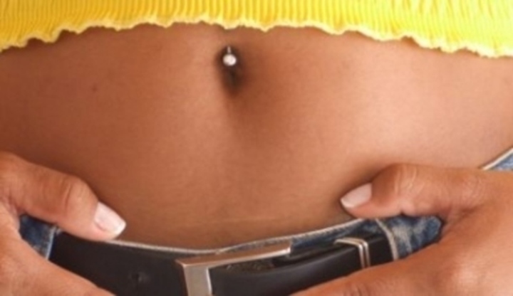 Ženské břicho s piercingem v pupíku 