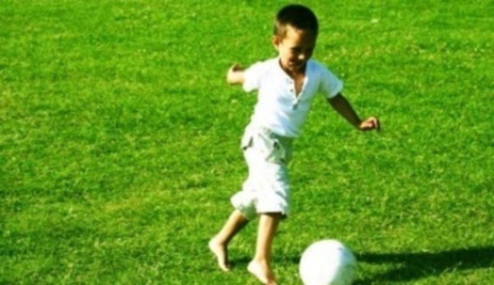 Chlapeček běhající za míčem po trávě