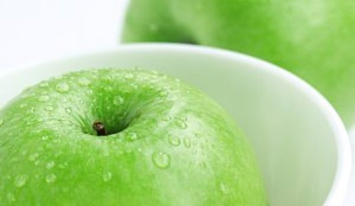Zelené jablko v bílé misce 