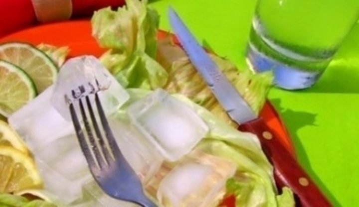 Kostky ledu na listech salátu s položeným příborem 