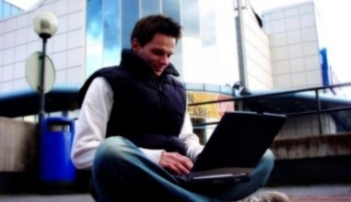 Muž sedící s notebookem v klíně