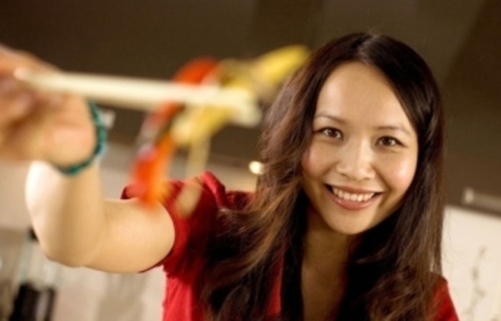 Žena držící v ruce čínské hůlky s jídlem 