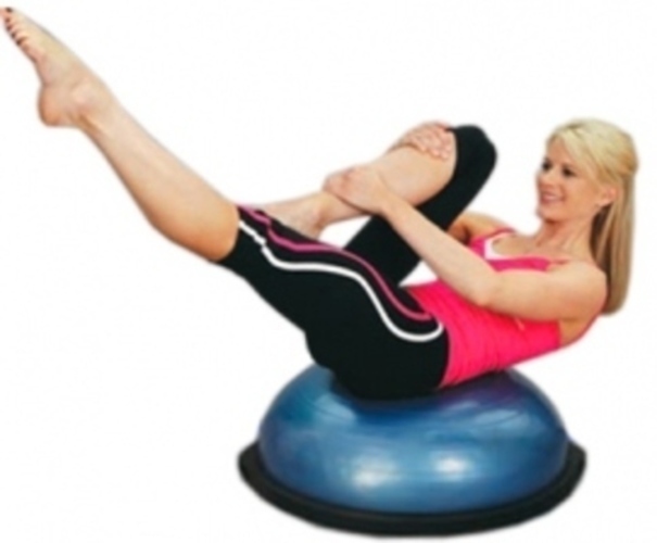 Žena sedící na cvičební pomůcce BOSU s jednou nohou nataženou