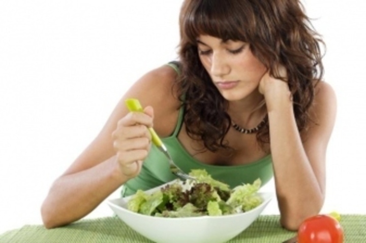 Žena pojídající zeleninový salát vidličkou