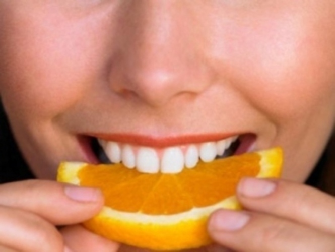 Zuby zakousnuté do plátku pomeranče