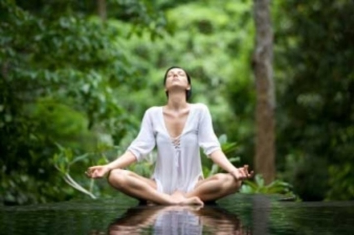 Žena sedící s překříženýma nohama a cvičící jógu