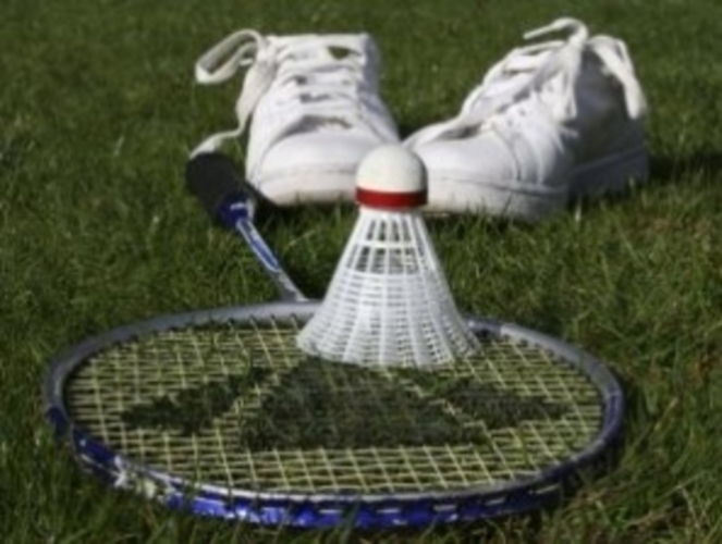 Badmintonová pálka s míčkem a botami na trávě 