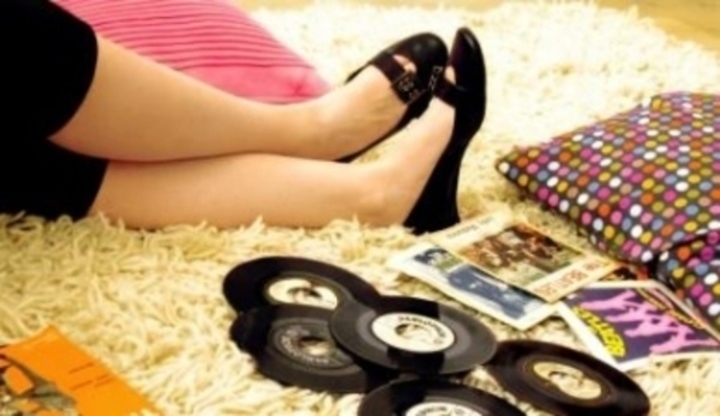 Nohy položené na koberci společně s gramofonovými deskami 