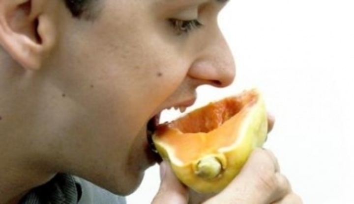 Muž s pootevřenými ústy držící plátek papaji