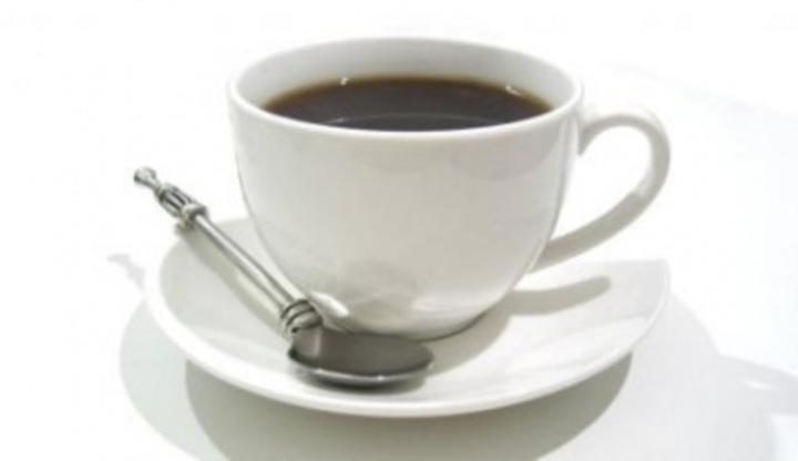 Plný šálek kávy se lžičkou položenou na talířku