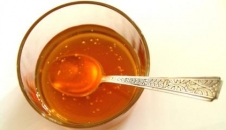Sklenice medu s ponořenou lžičkou