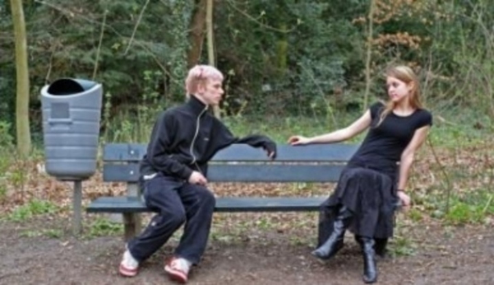 Muž se ženou sedící na lavičce daleko od sebe