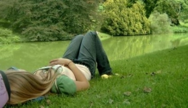 Žena ležící na louce u potoka 