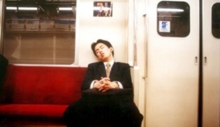 Muž spící v metru na lavici 