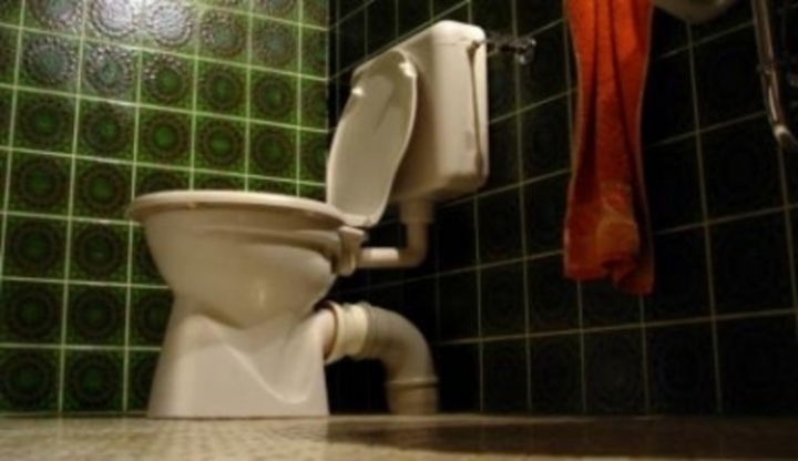 Bílý záchod v místnosti ze zelených kachliček