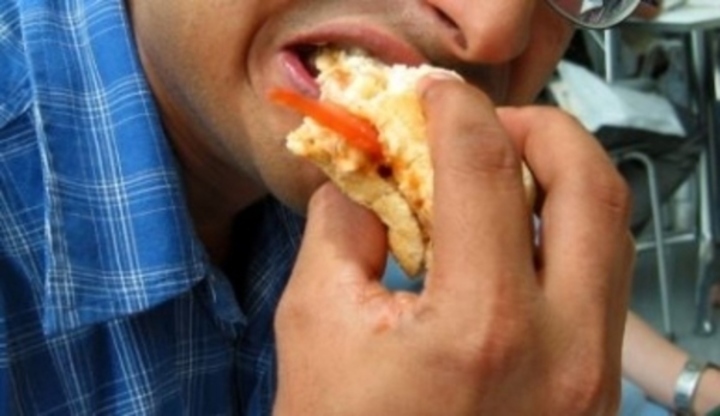 Muž dávající si jídlo do úst 