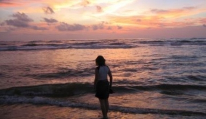 Žena stojící u moře po západu slunce 