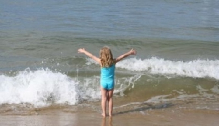 Dítě s roztaženýma rukama u moře 