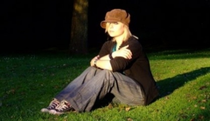 Žena s čepicí sedící na trávě 