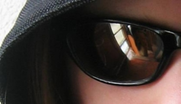 Oko osoby schované pod slunečními brýlemi 